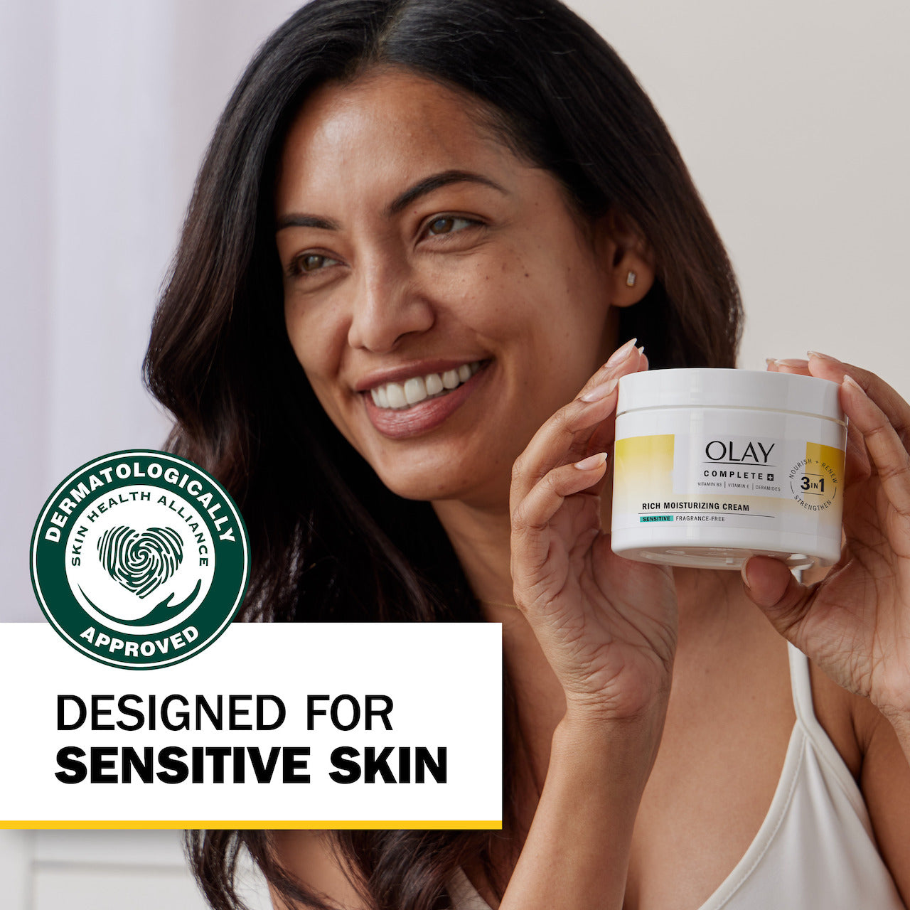 Model posing with Olay Complete + Rich Moisturizing Cream container smiling. Sensitive Designed for sensitive skin. Dermatologically approved. Model posing with Olay Complete + Rich Moisturizing Cream container smiling. Sensitive Designed for sensitive skin. Dermatologically approved.