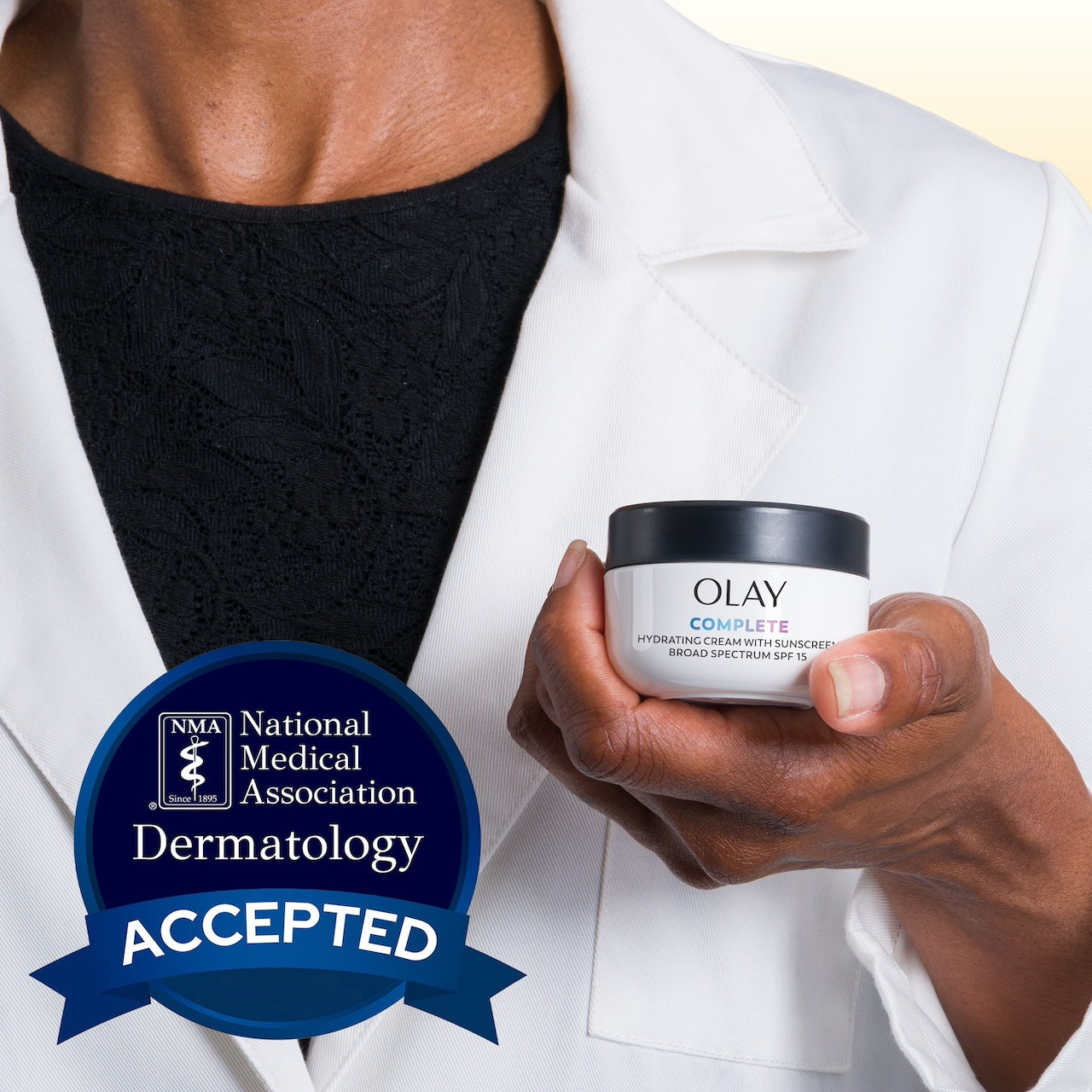 Model wearing lab coat holding Olay Complete Cream Moisturizer with SPF 15 Normal container. National medical association dermatology accepted. Model wearing lab coat holding Olay Complete Cream Moisturizer with SPF 15 Normal container. National medical association dermatology accepted.