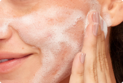 Person cleansing their face with foamy wash