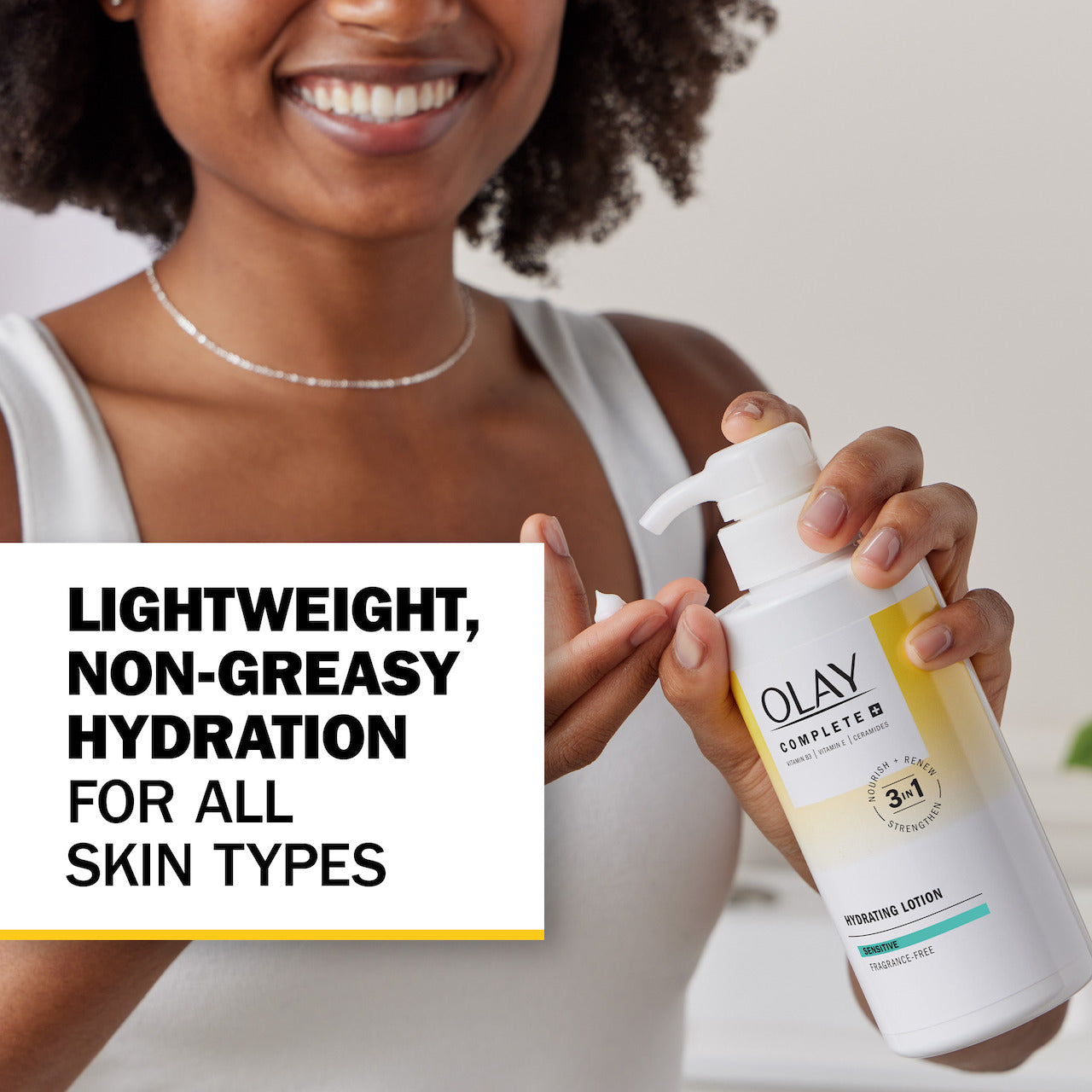 Model posing with Olay Complete + Hydrating Lotion Sensitive bottle with pump applying lotion to fingers. Lightweight, non greasy hydration for all skin types.