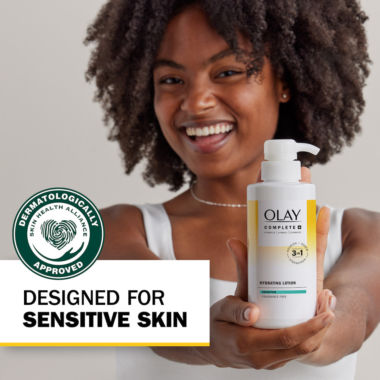 Model posing with Complete + Hydrating Lotion bottle smiling. Designed for sensitive skin. Dermatologically approved.