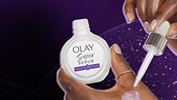 A person squeezing a drop of Olay Super Serum Night Repair on the back of their hand.
