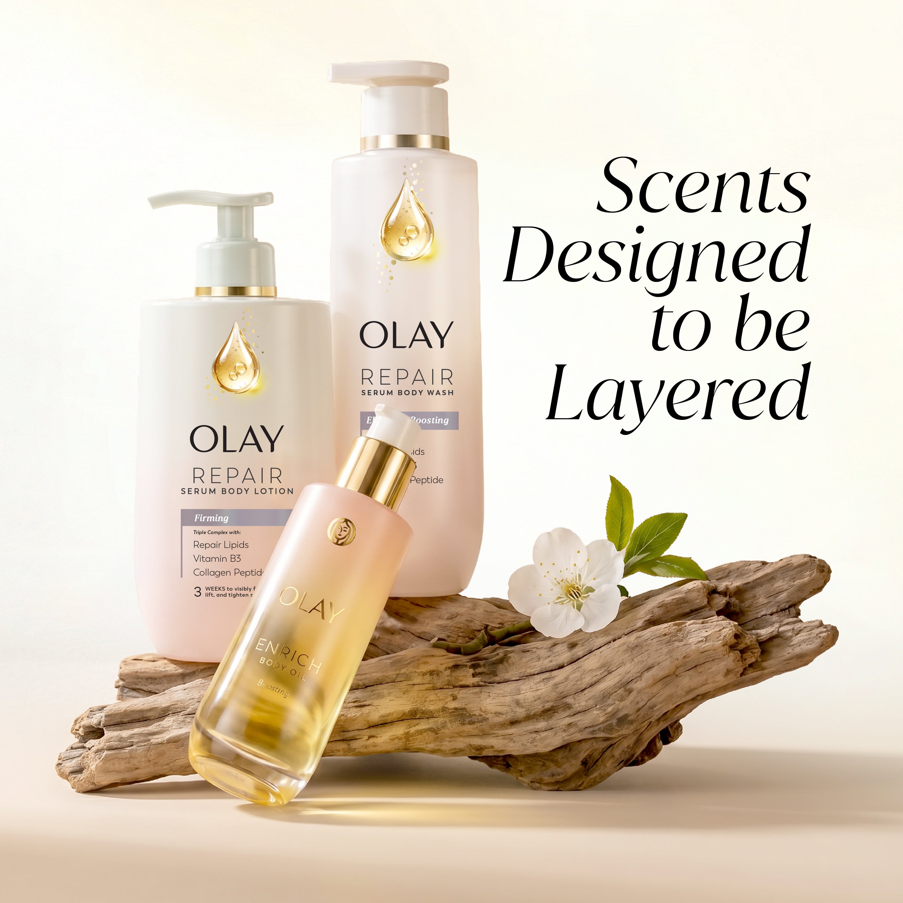 Three Olay Repair skincare products arranged on a piece of driftwood with a white flower, against a warm cream background. Text on the right reads 'Scents Designed to be Layered.