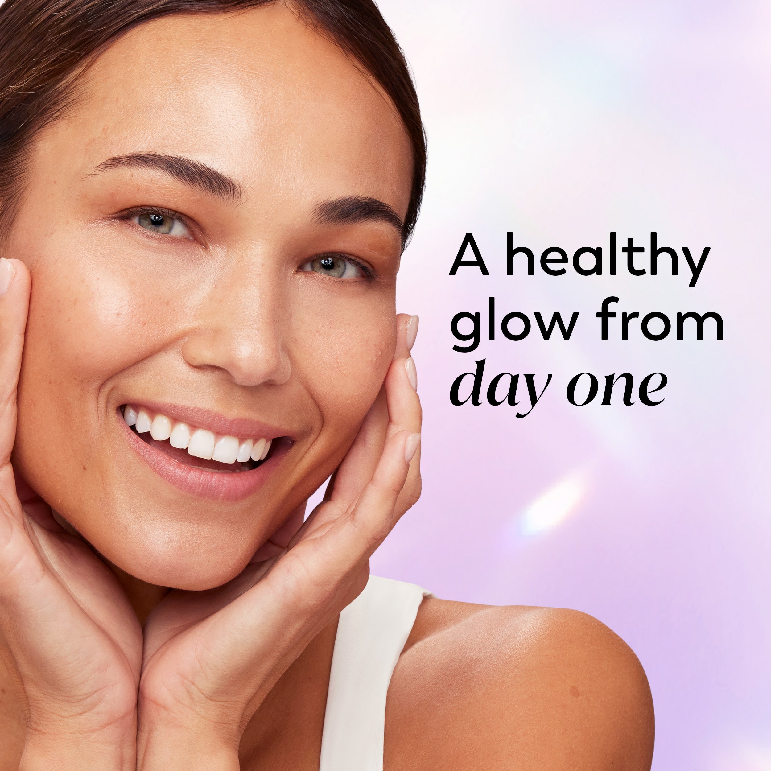 A smiling woman with clear skin poses with her hands on her cheeks against a soft pastel purple background, with the text 'A healthy glow from day one' on the right.