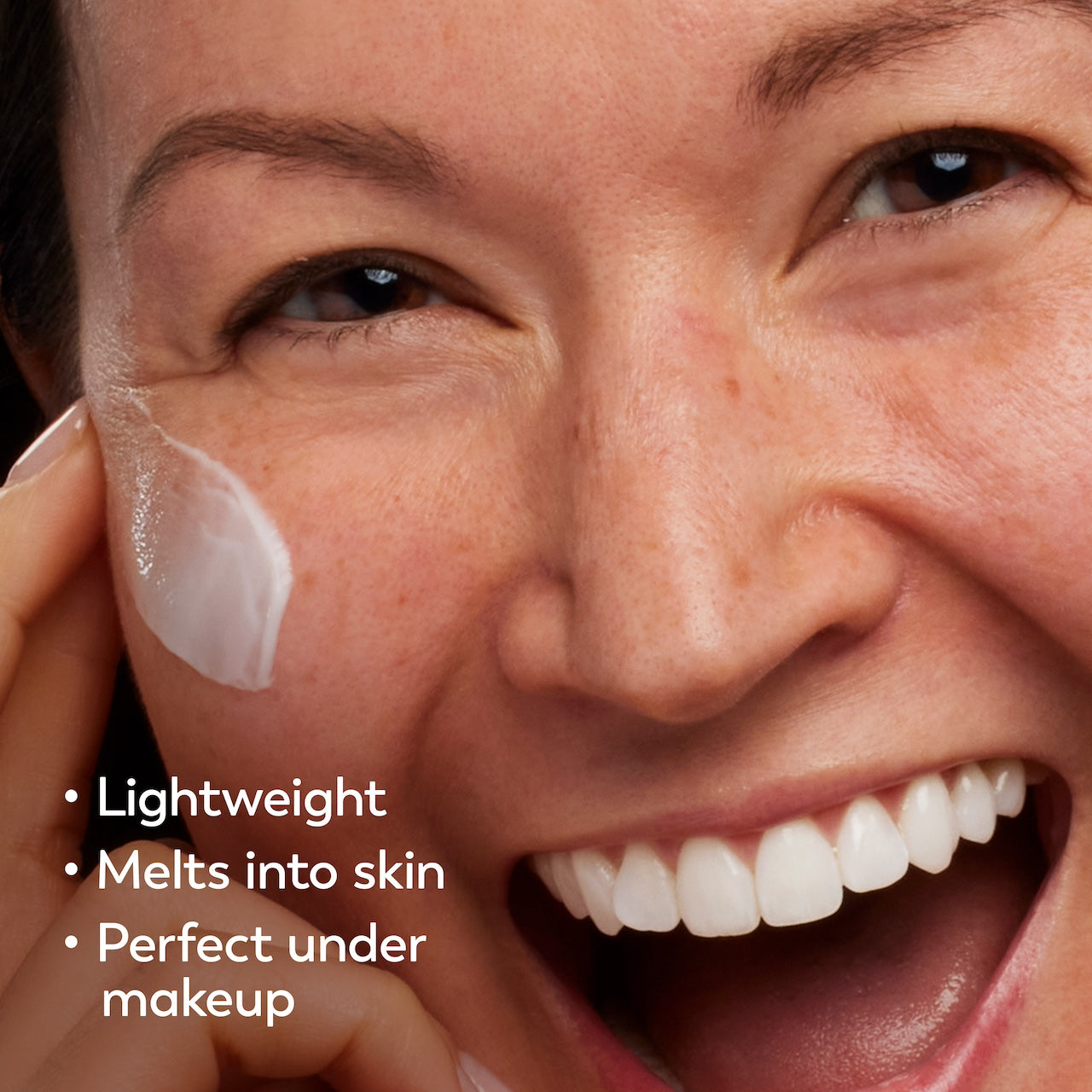 Model posing and smiling applying Vitamin C MAX Lightweight Hydrating Moisturizer to face. Lightweight, melts into skin, perfect under makeup