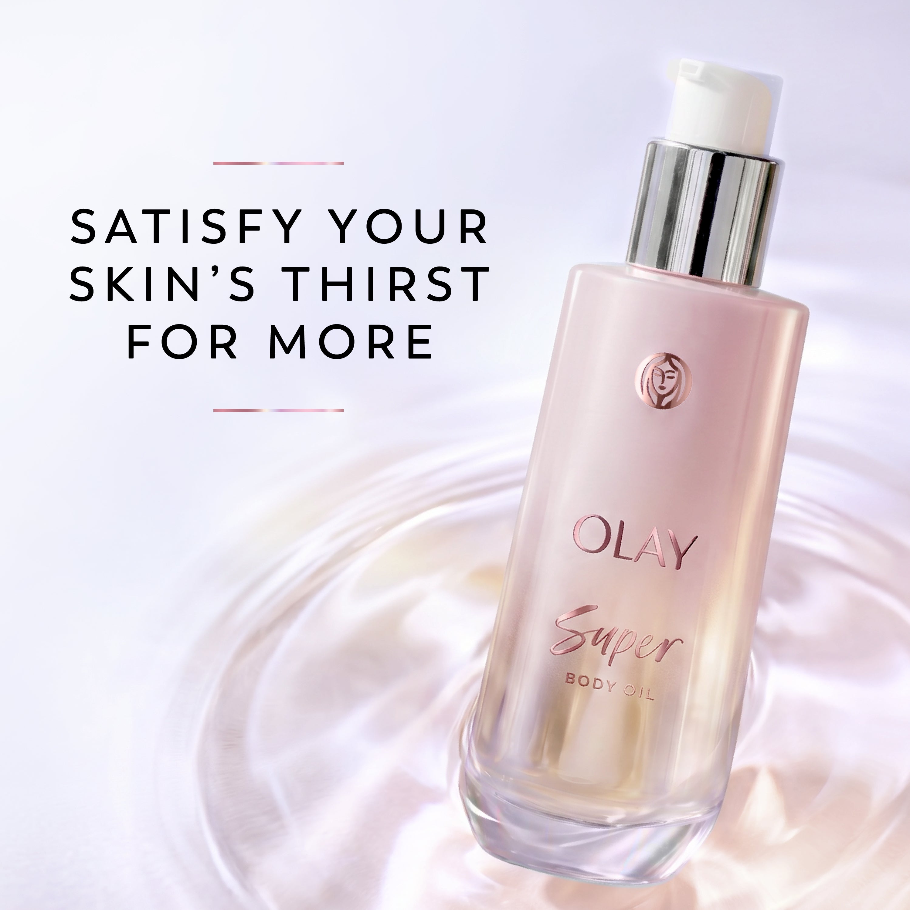 Olay Super Body Oil bottle in a soft pink frosted glass finish with a silver pump and white cap, shown on a light background with promotional text reading 'SATISFY YOUR SKIN'S THIRST FOR MORE'.