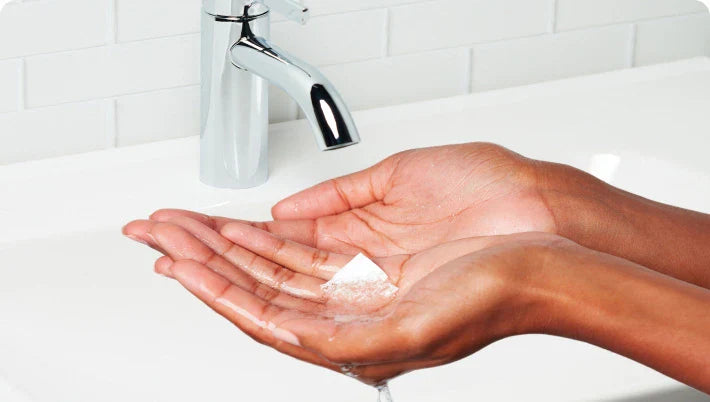 Hands under running water with soap in a bathroom setting