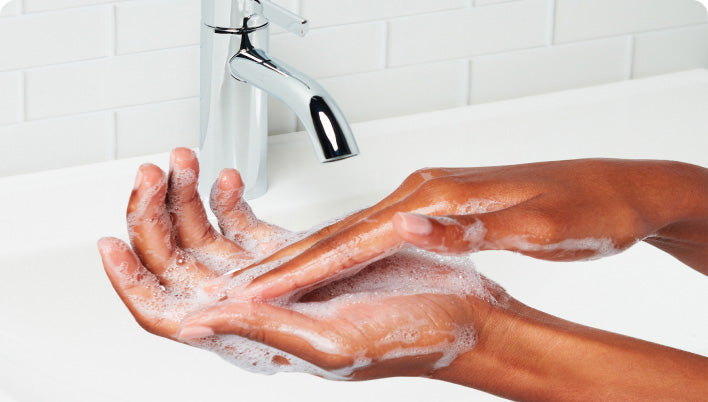Hands being washed with soap under a faucet in a bathroom setting
