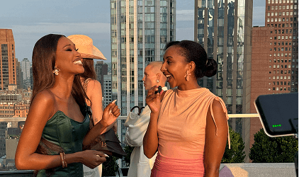 Two women during an interview at an Olay rooftop event, with a city skyline in the background.