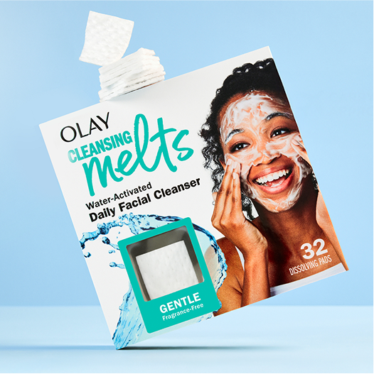 Olay Cleansing Melts packaging with a woman applying the product on a blue background