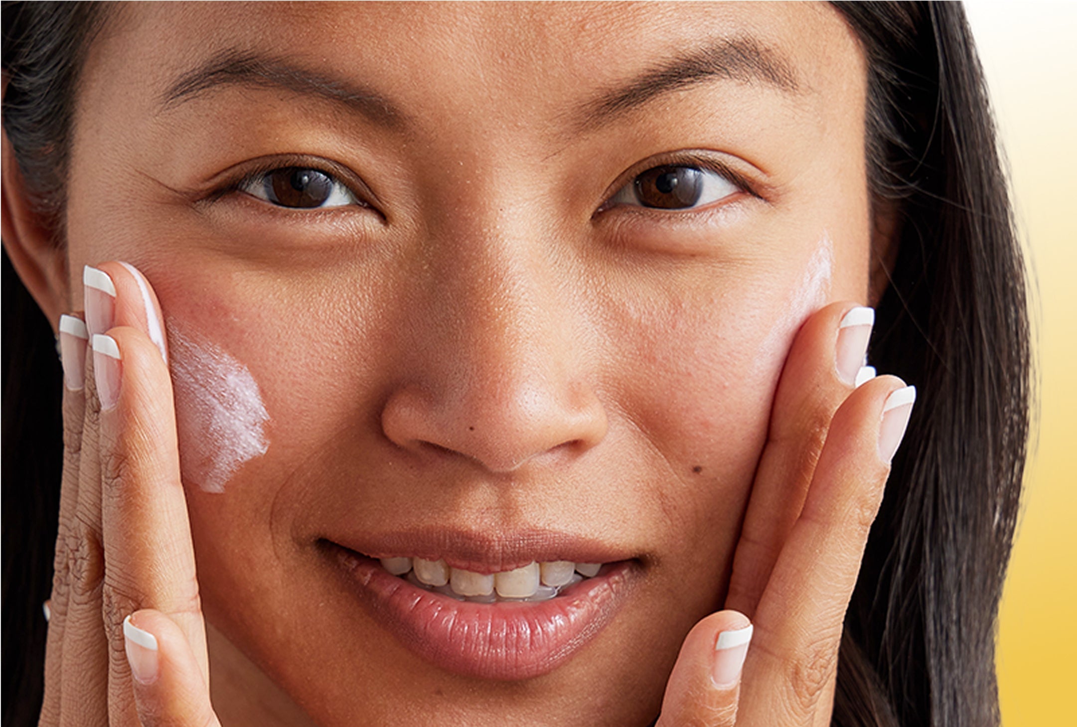 Woman applying cream to her face with a blurred background