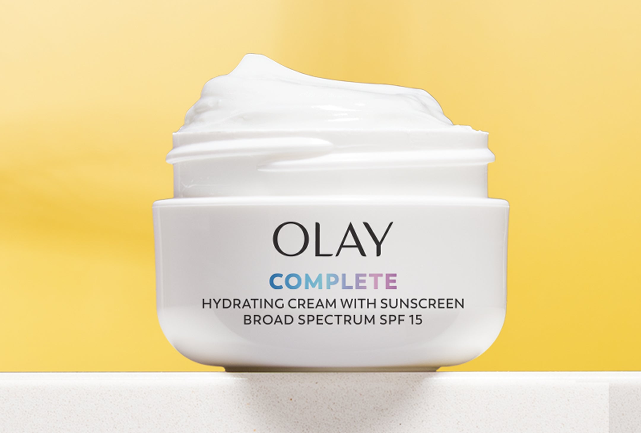 Olay Complete Hydrating Cream with Sunscreen jar on a yellow background
