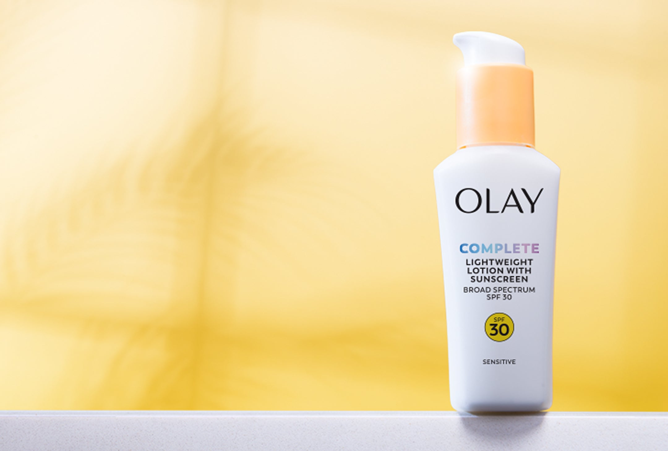 Olay sunscreen lotion bottle on a yellow background