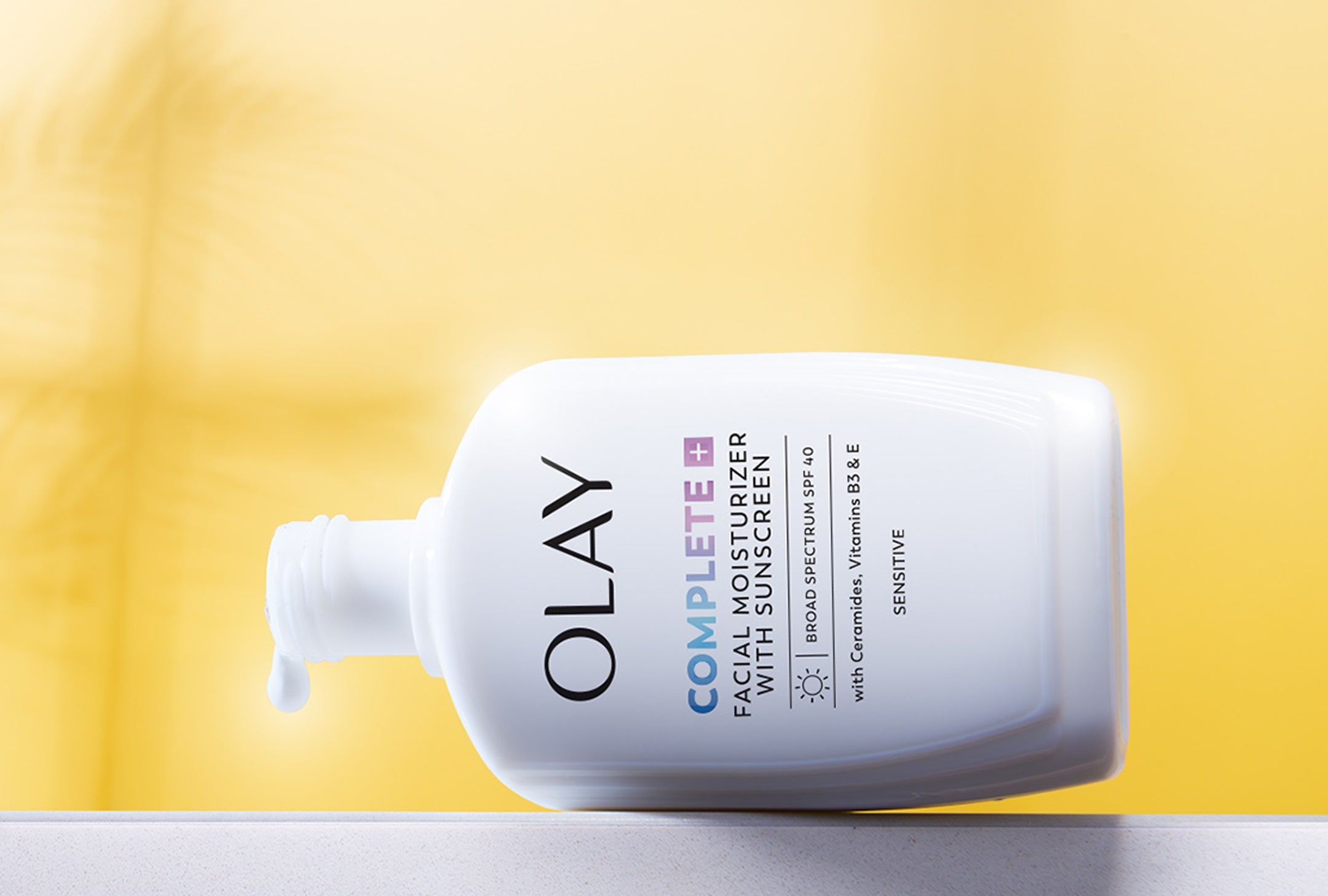 Olay Complete All Day Moisturizer with Sunscreen bottle on a yellow background