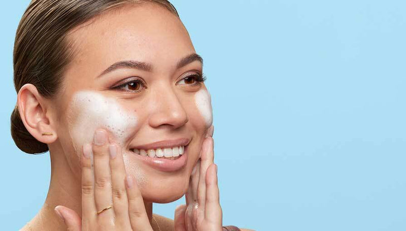 Woman applying cream to her face against a light blue background
